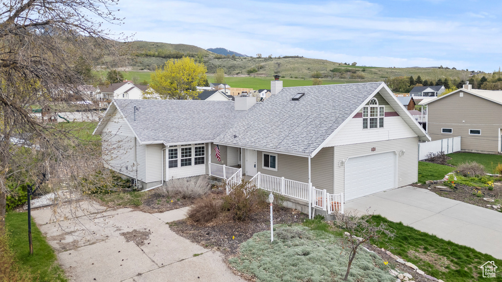 Ranch-style home featuring covered porch, concrete driveway, a shingled roof, and a chimney