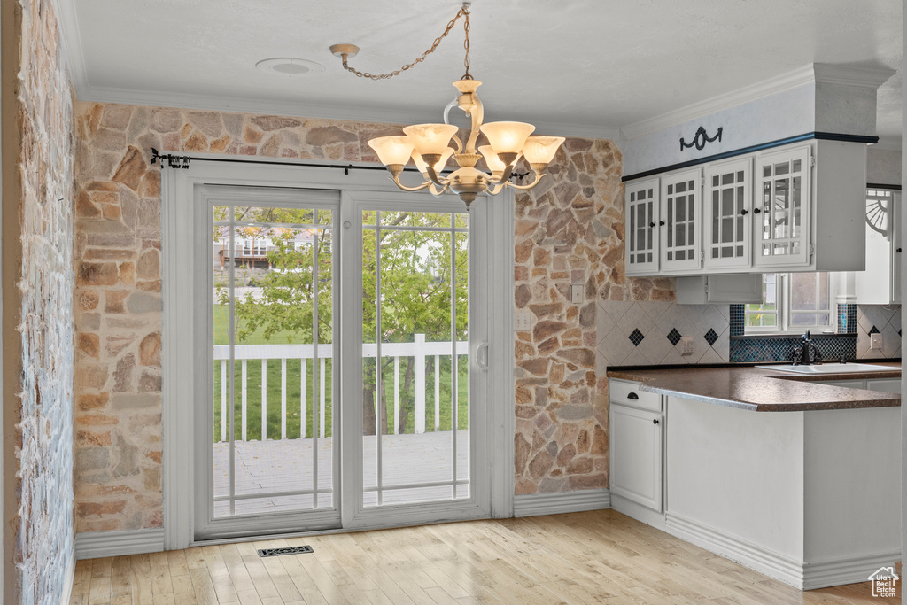 Kitchen with dark countertops, a notable chandelier, ornamental molding, and a healthy amount of sunlight