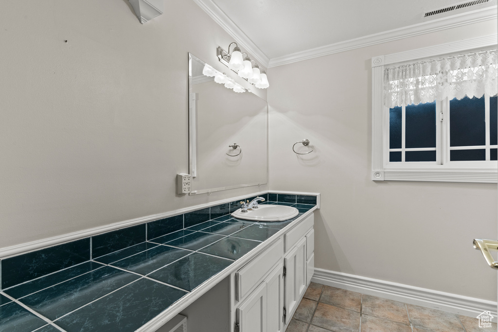 Bathroom with visible vents, ornamental molding, baseboards, and vanity