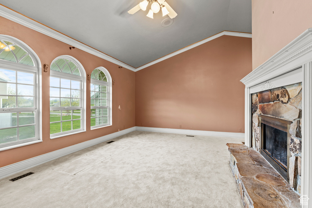 Unfurnished living room featuring a stone fireplace, visible vents, vaulted ceiling, baseboards, and carpet flooring