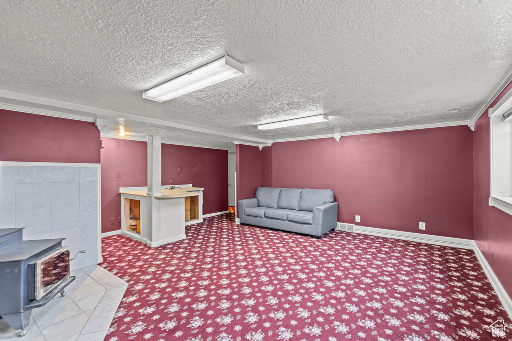 Interior space featuring carpet floors, a wood stove, a textured ceiling, and visible vents