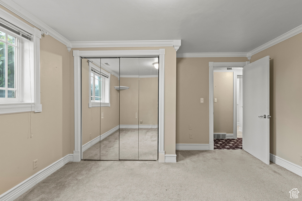 Unfurnished bedroom featuring carpet floors, ornamental molding, baseboards, and a closet