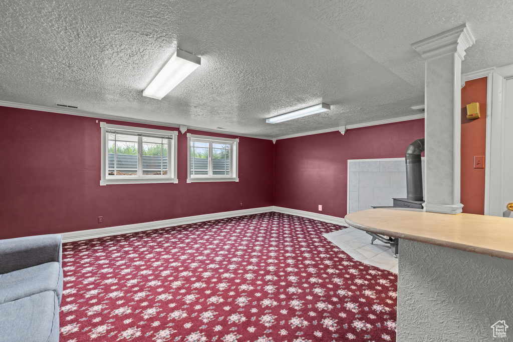 Unfurnished office with carpet floors, a textured ceiling, visible vents, and a wood stove