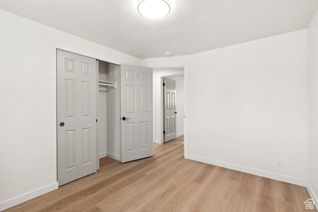 Unfurnished bedroom with baseboards, light wood-style flooring, and a closet