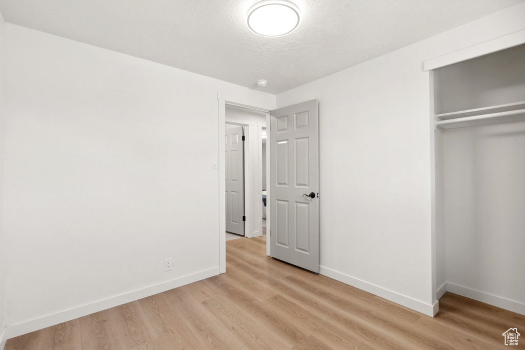Unfurnished bedroom featuring baseboards, light wood-style floors, and a closet