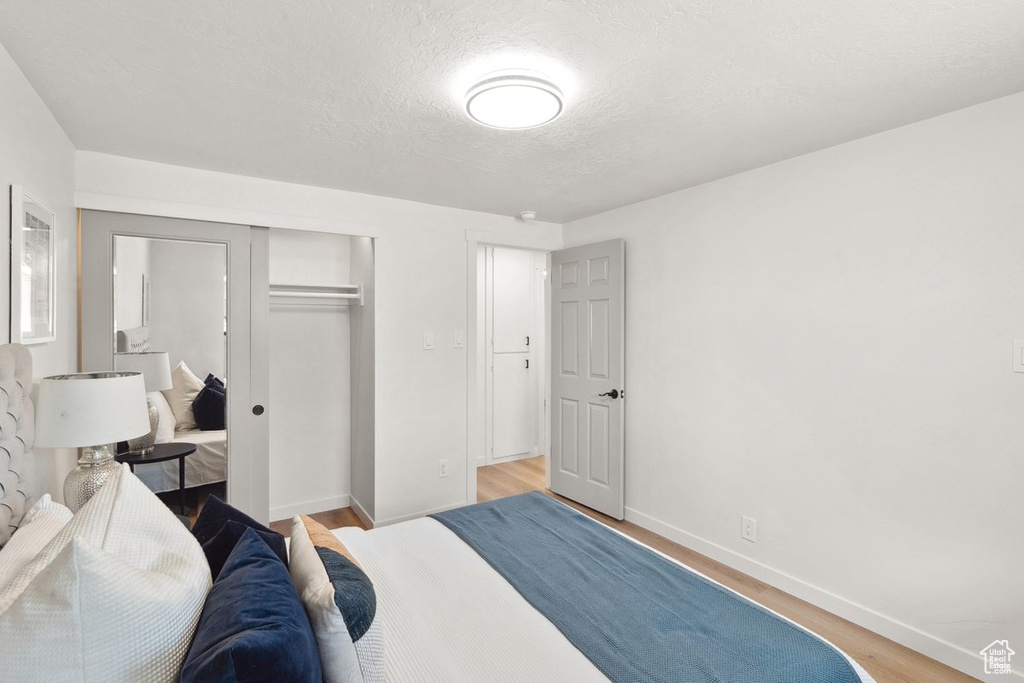 Bedroom featuring baseboards, a closet, light wood finished floors, and a textured ceiling