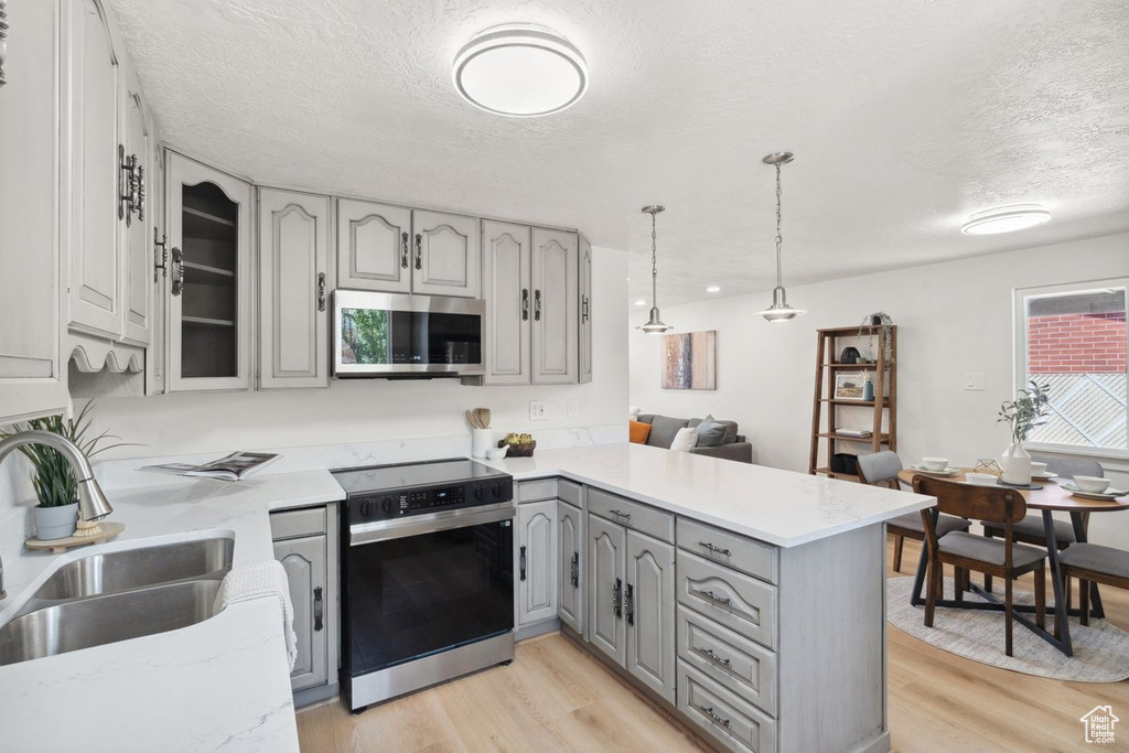 Kitchen featuring stainless steel microwave, electric stove, gray cabinetry, a peninsula, and a sink