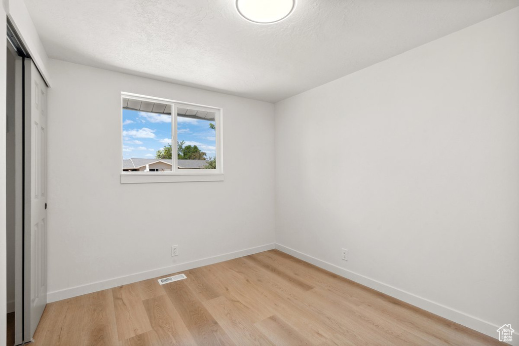 Unfurnished bedroom with light wood-style floors, a closet, baseboards, and a textured ceiling