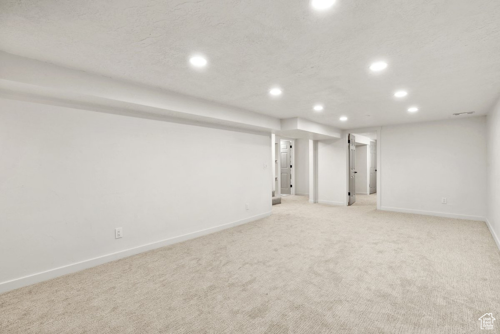 Finished basement with recessed lighting, baseboards, light carpet, and a textured ceiling