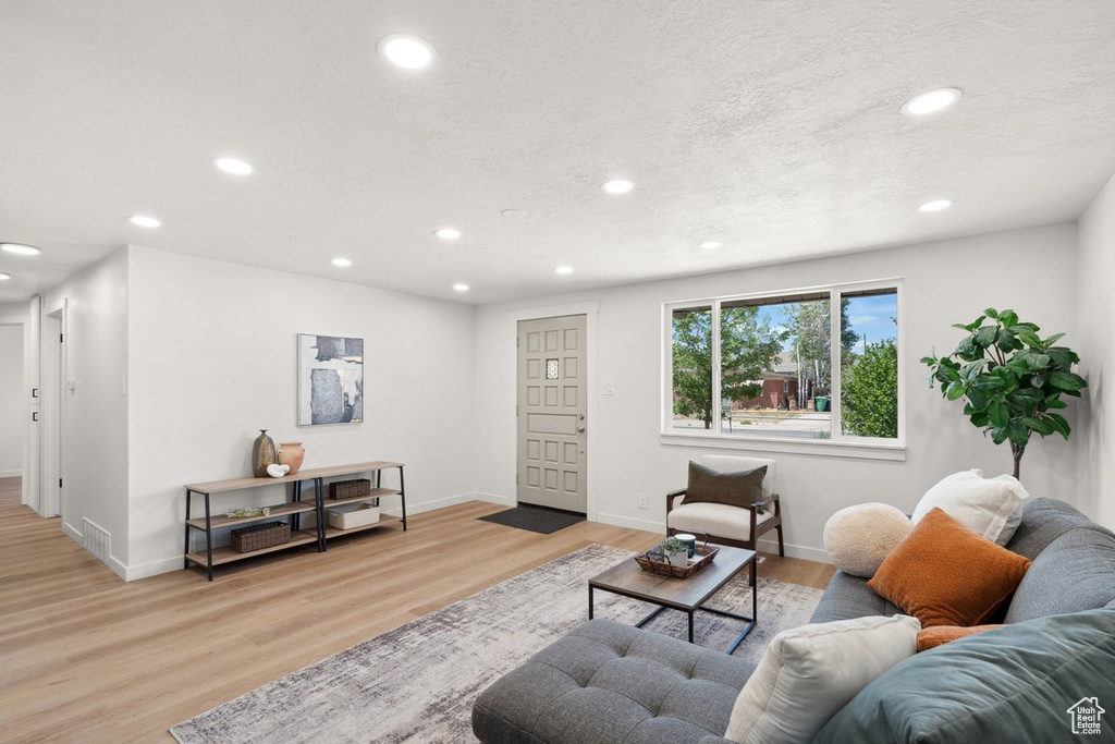 Living area featuring recessed lighting, wood finished floors, baseboards, and a textured ceiling