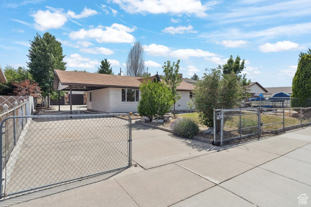 View of front facade with a gate, an attached carport, and brick siding