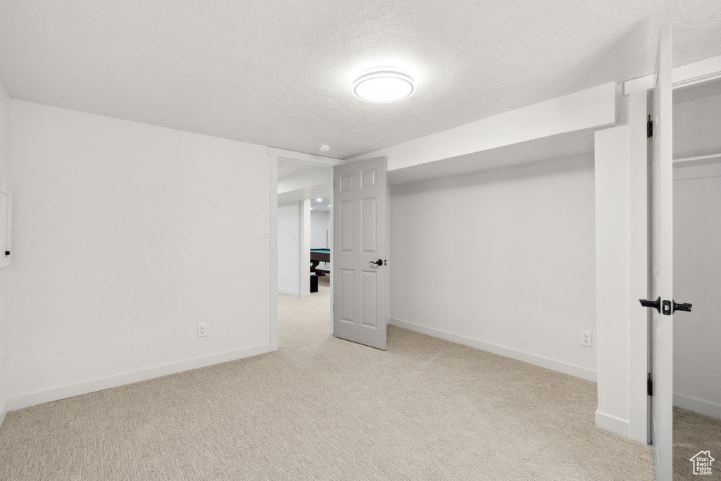Finished below grade area featuring carpet, baseboards, and a textured ceiling