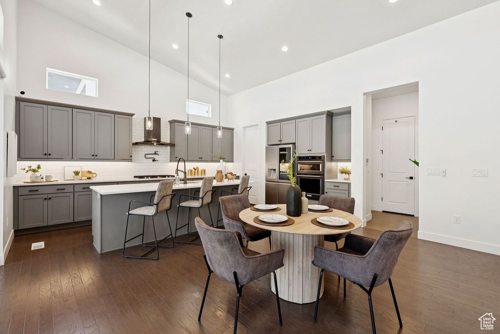 Dining space featuring high vaulted ceiling, dark wood-style floors, and baseboards