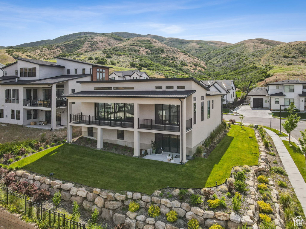 Back of property featuring stucco siding, a balcony, and a mountain view