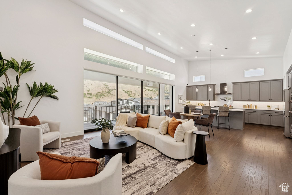 Living room with a towering ceiling, recessed lighting, and dark wood-style flooring