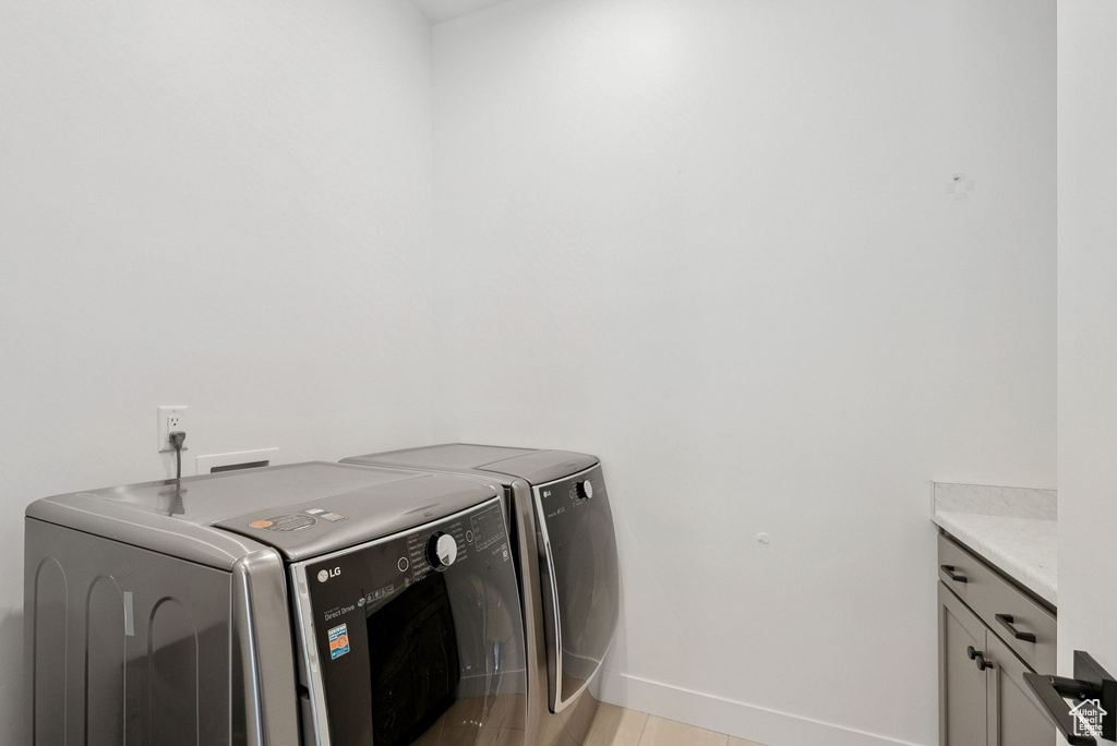 Laundry room with separate washer and dryer, cabinet space, and baseboards