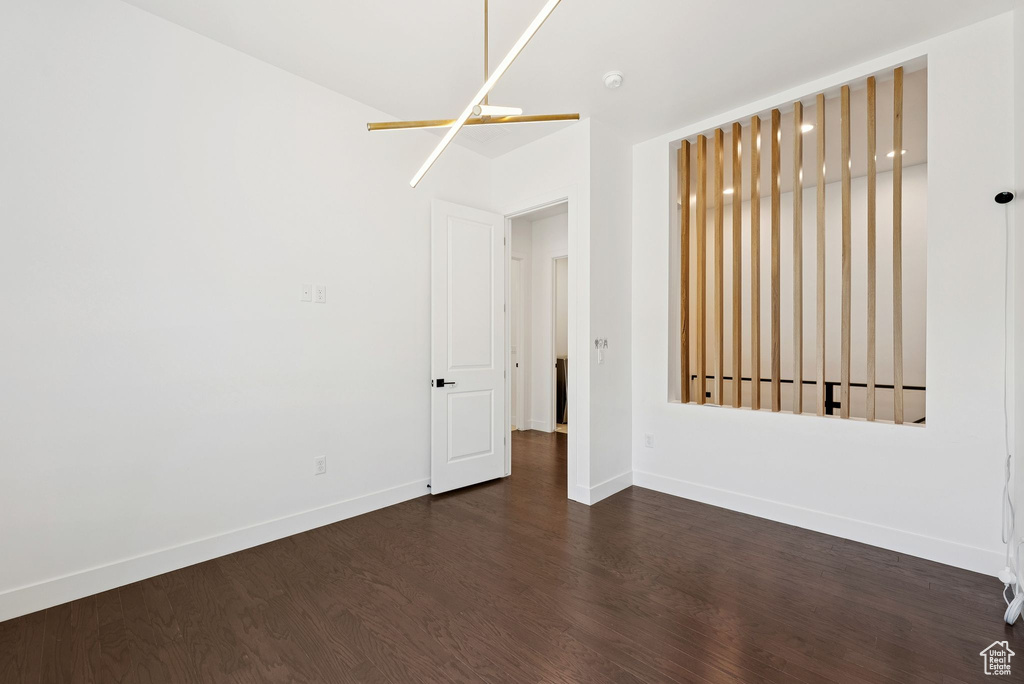 Empty room with dark wood-style flooring, baseboards, and a smoke detector