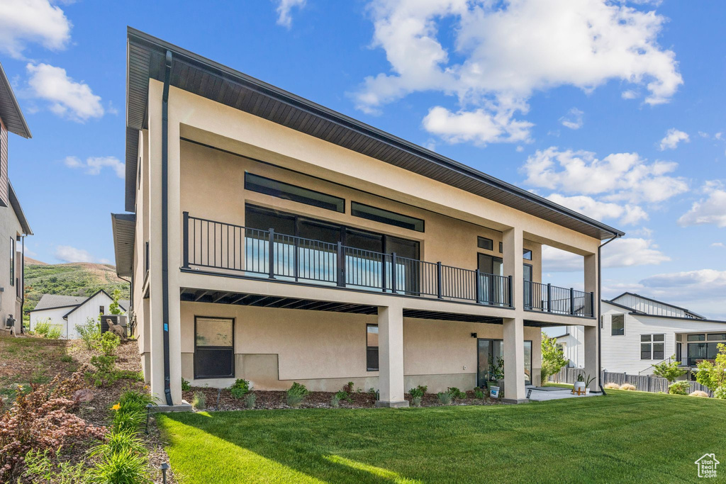 Rear view of property featuring a balcony and stucco siding
