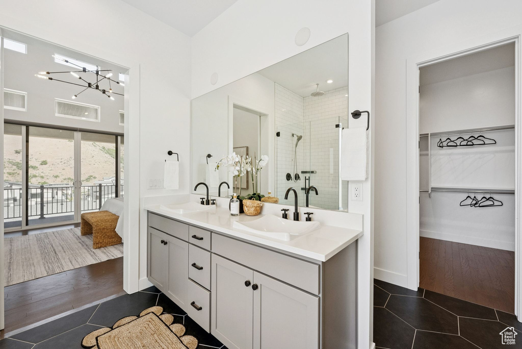 Ensuite bathroom with tile patterned floors, double vanity, a shower stall, a chandelier, and a spacious closet
