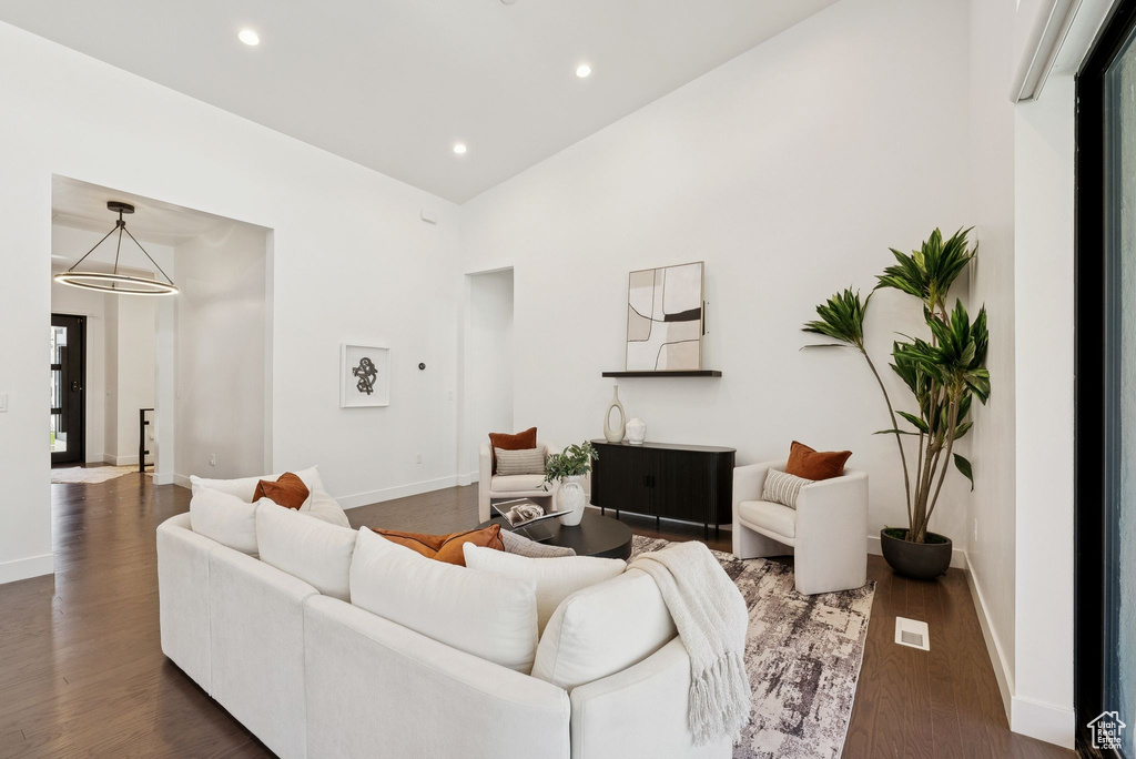 Living room with baseboards, recessed lighting, wood finished floors, and high vaulted ceiling