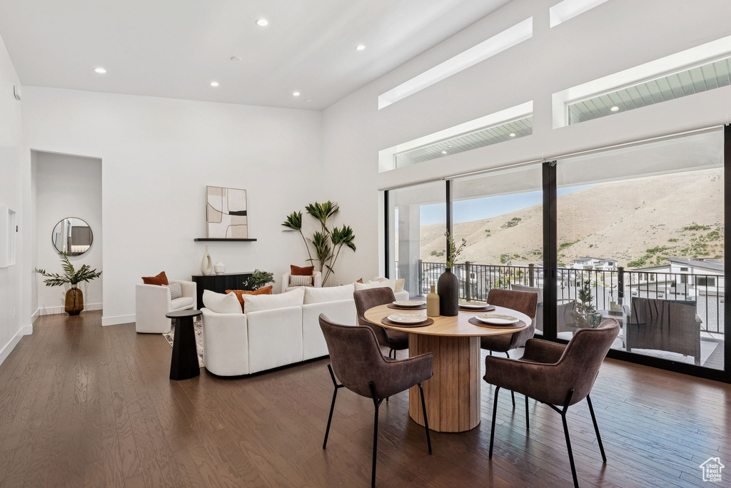 Dining room featuring dark wood-style flooring, a towering ceiling, a mountain view, baseboards, and recessed lighting