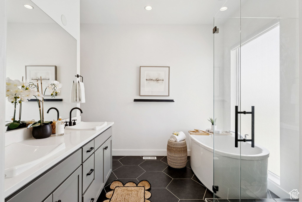 Bathroom with double vanity, a soaking tub, tile patterned floors, baseboards, and recessed lighting