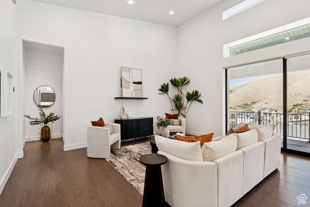 Living area with healthy amount of natural light, dark wood-type flooring, a high ceiling, baseboards, and recessed lighting
