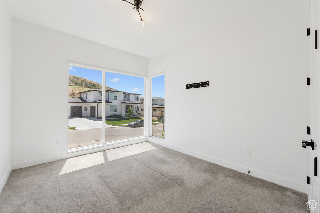 Carpeted spare room featuring baseboards and a residential view