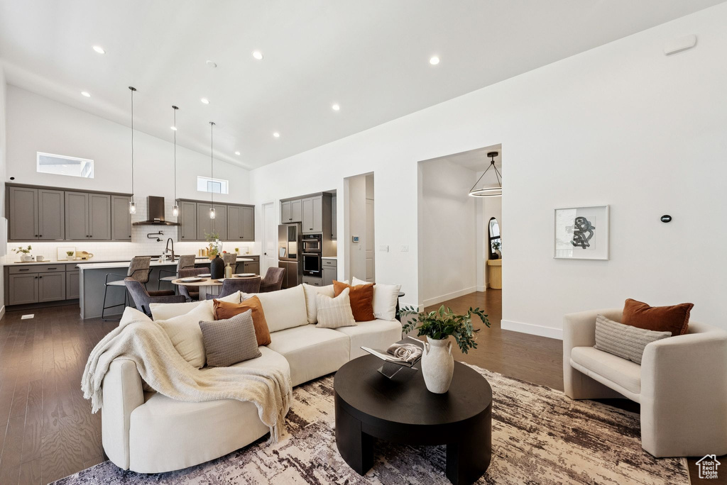 Living room featuring dark wood-type flooring, high vaulted ceiling, recessed lighting, and baseboards