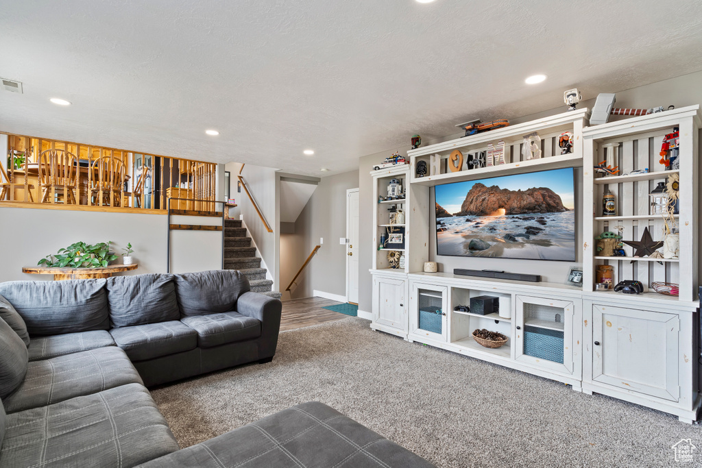 Carpeted living area featuring stairs, visible vents, baseboards, and recessed lighting