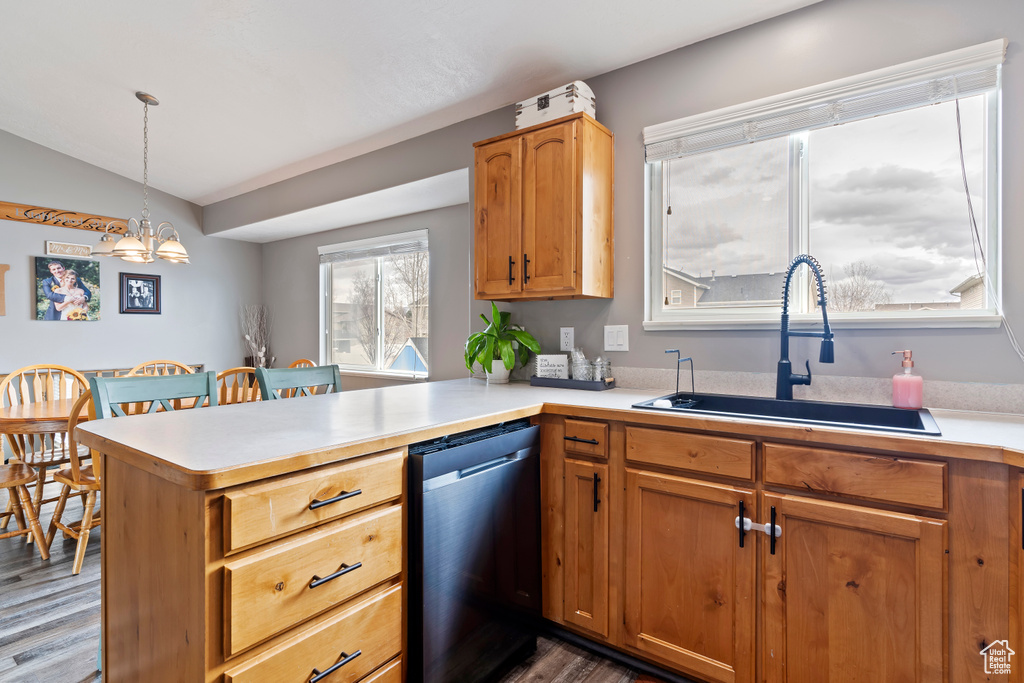Kitchen featuring light countertops, a chandelier, a peninsula, dishwasher, and a sink
