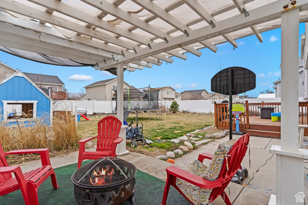 View of patio / terrace with a trampoline, a fenced backyard, a deck, a fire pit, and an outdoor structure