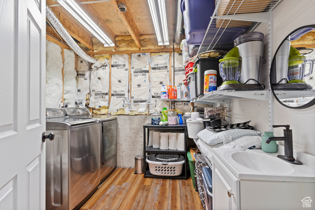 Washroom with washing machine and clothes dryer, a sink, laundry area, and light wood-style floors