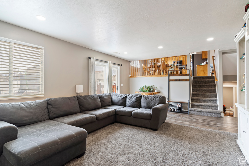 Living room with wood finished floors, a textured ceiling, stairway, and recessed lighting