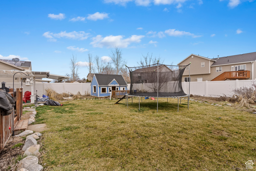View of yard with a fenced backyard, a shed, an outdoor structure, and a trampoline