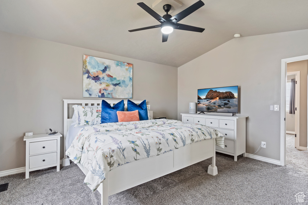 Carpeted bedroom featuring a ceiling fan, baseboards, and vaulted ceiling