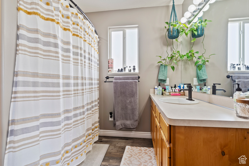 Full bathroom with baseboards, wood finished floors, vanity, and a shower with curtain