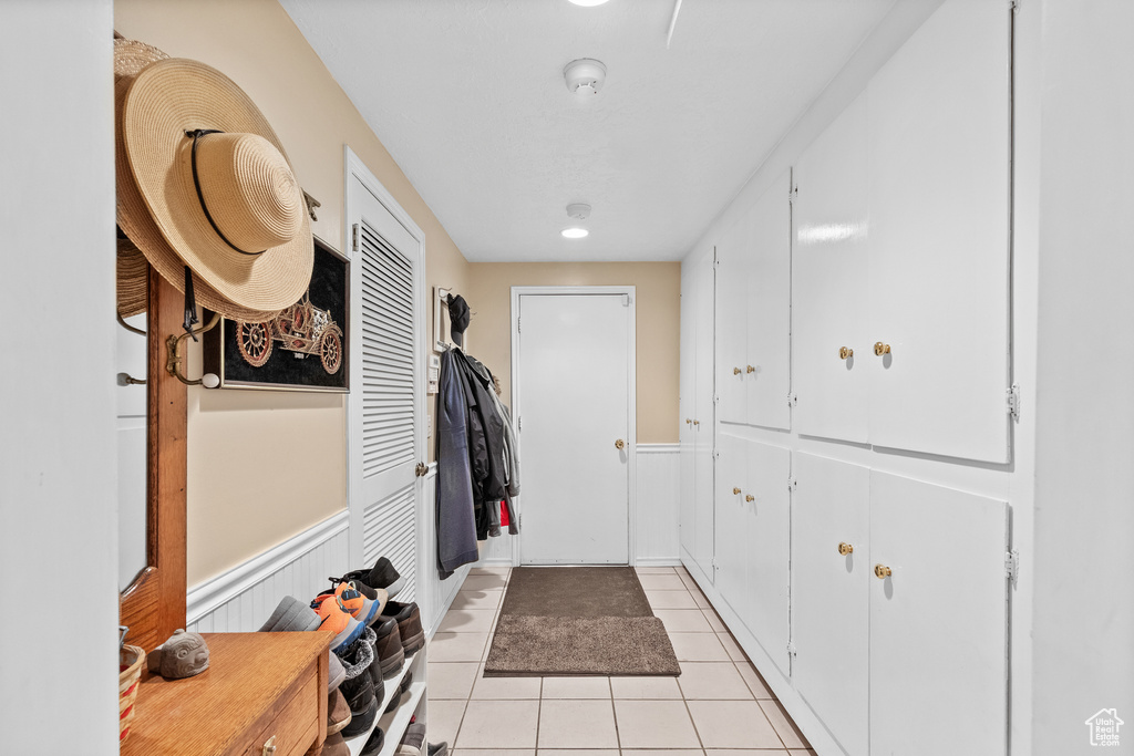 Doorway featuring light tile patterned floors and a wainscoted wall