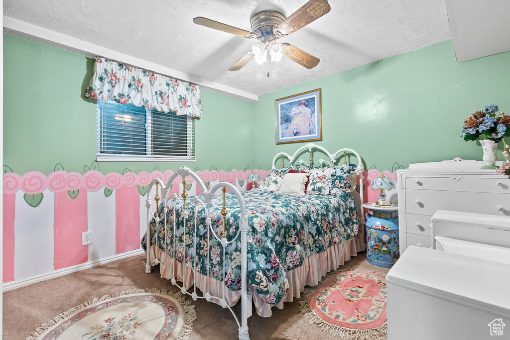 Carpeted bedroom featuring a textured ceiling and a ceiling fan