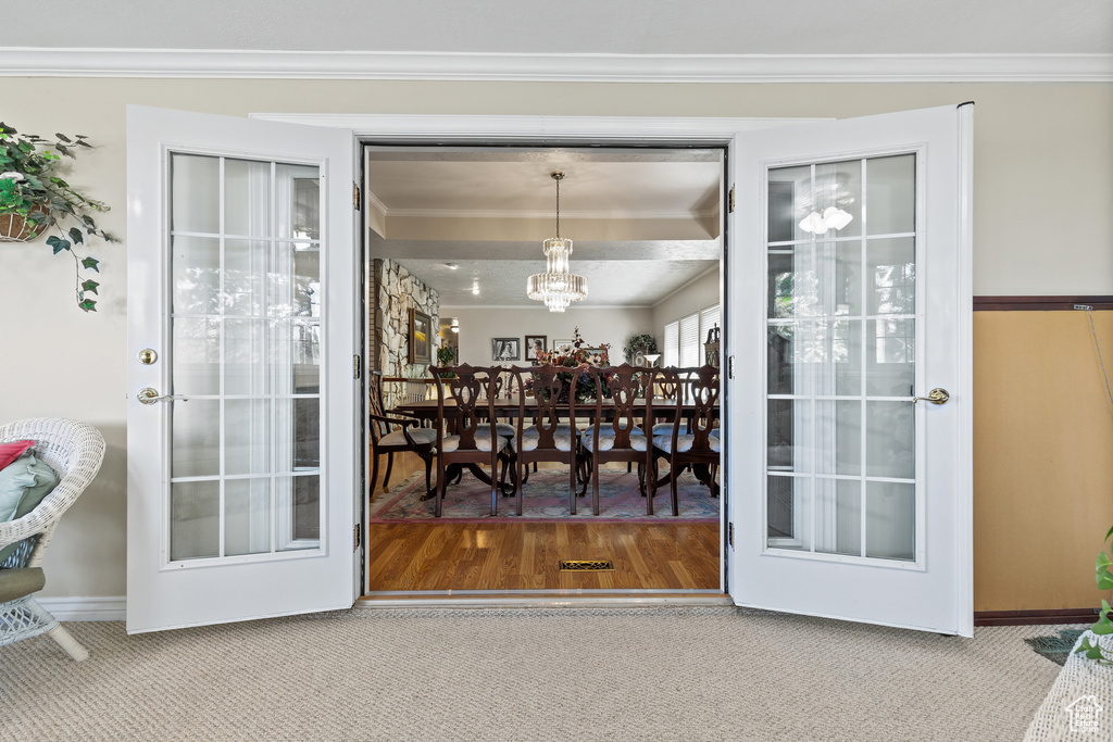 Entryway with ornamental molding, carpet, and a chandelier