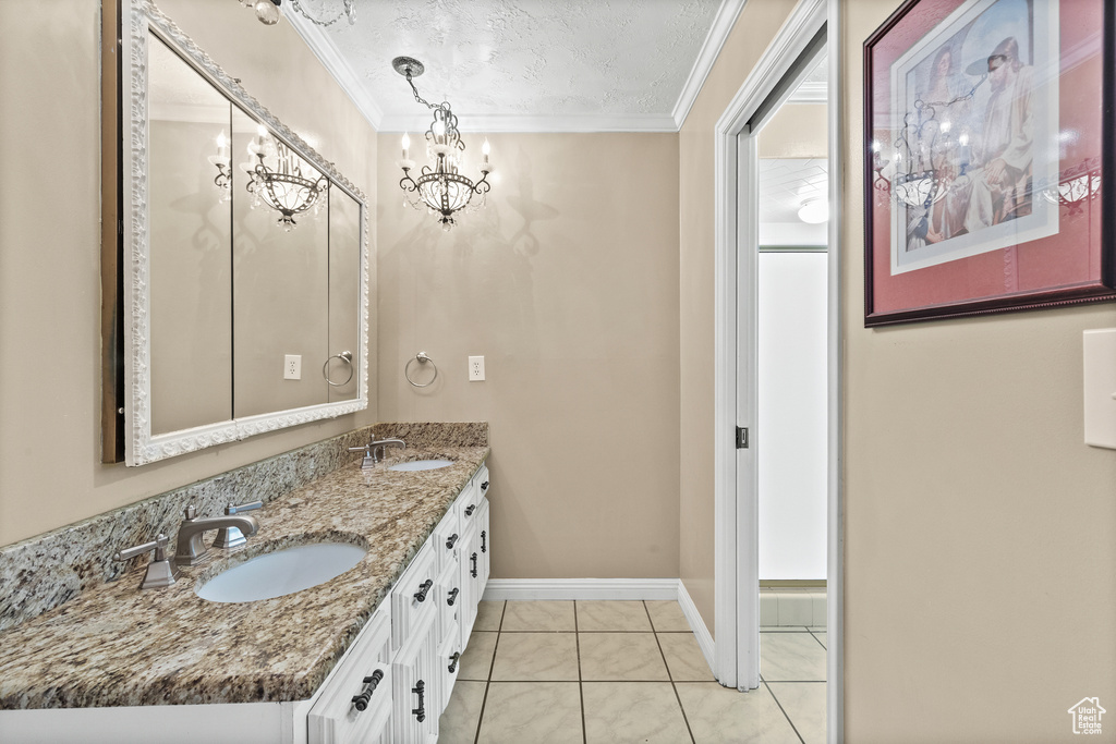 Full bath with ornamental molding, double vanity, a chandelier, and tile patterned floors
