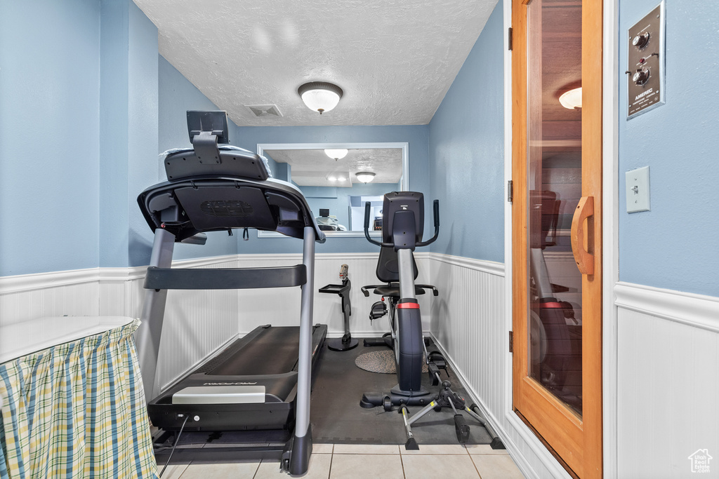 Workout room featuring wainscoting and a textured ceiling