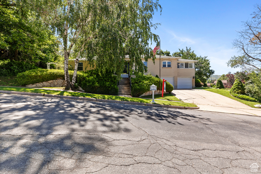 View of front of home featuring concrete driveway, an attached garage, and stairs