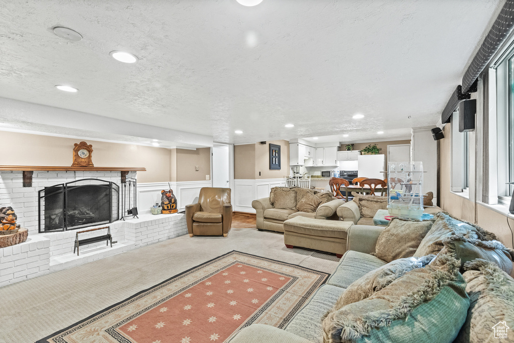 Carpeted living area with a brick fireplace, recessed lighting, and wainscoting