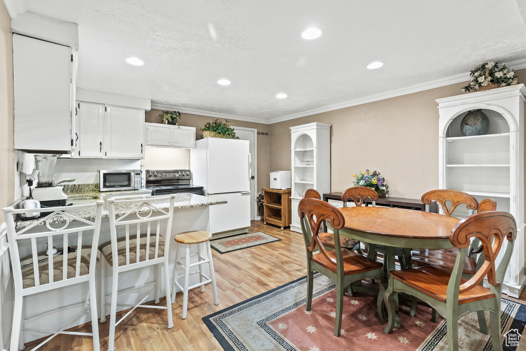 Dining area with crown molding, light wood-type flooring, and recessed lighting