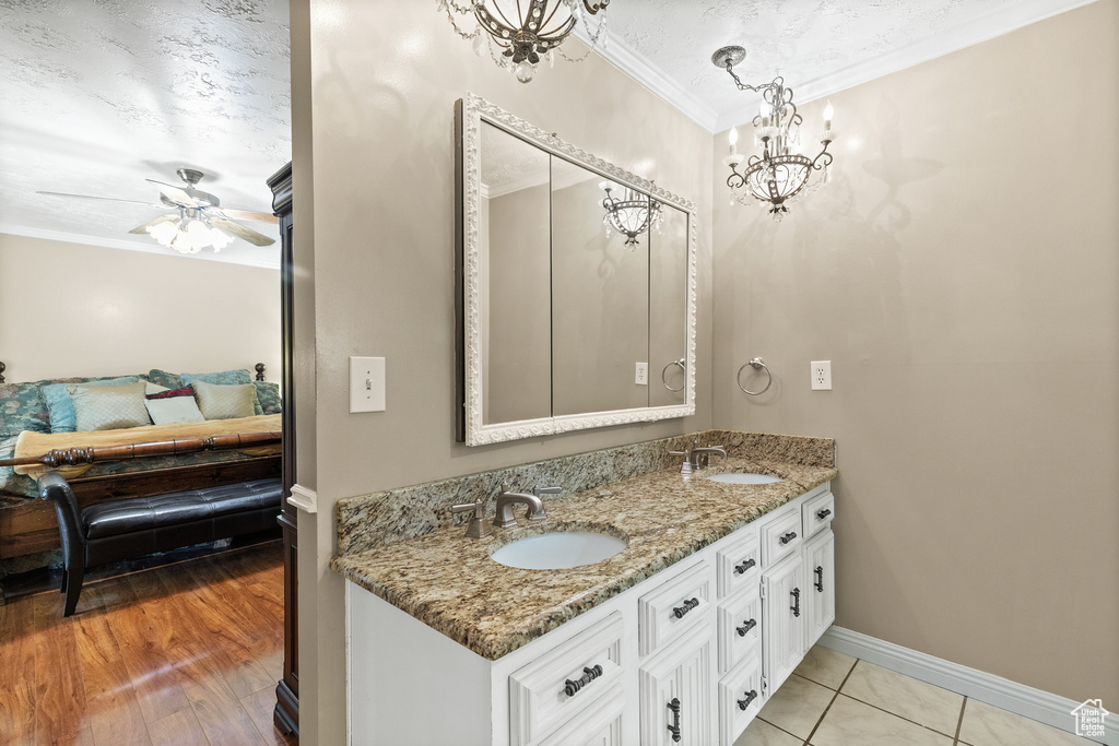 Ensuite bathroom featuring crown molding, double vanity, a chandelier, and a ceiling fan
