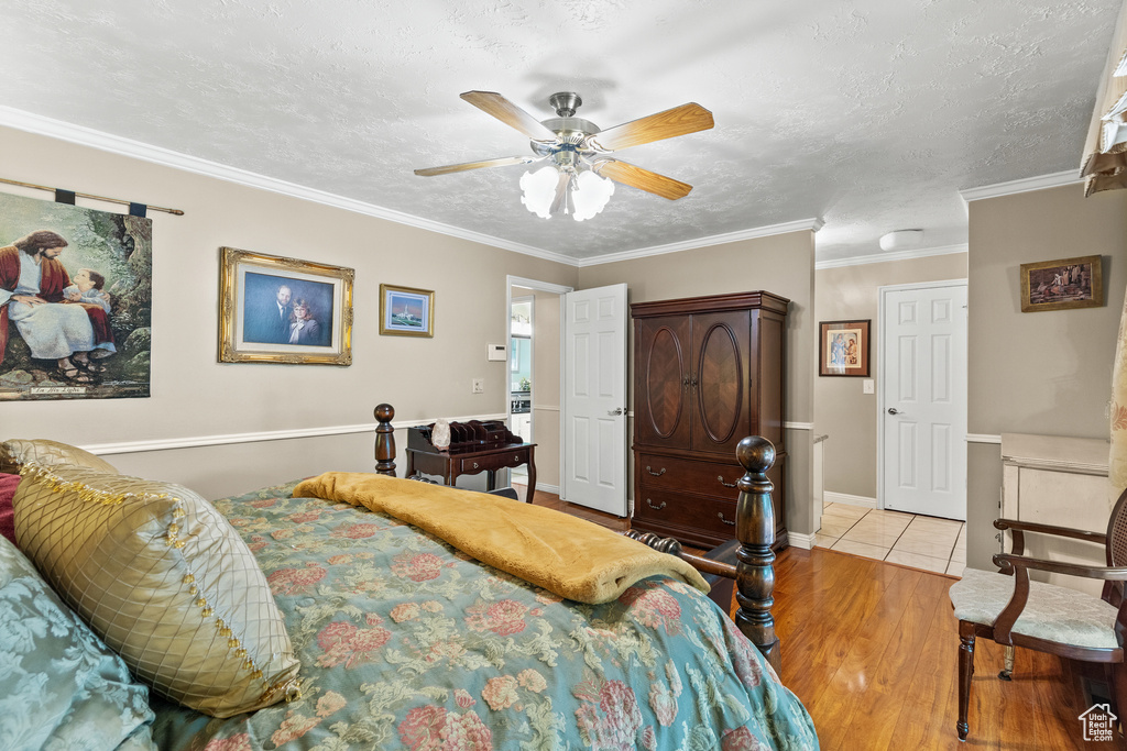 Bedroom featuring wood finished floors, ornamental molding, a ceiling fan, and a textured ceiling