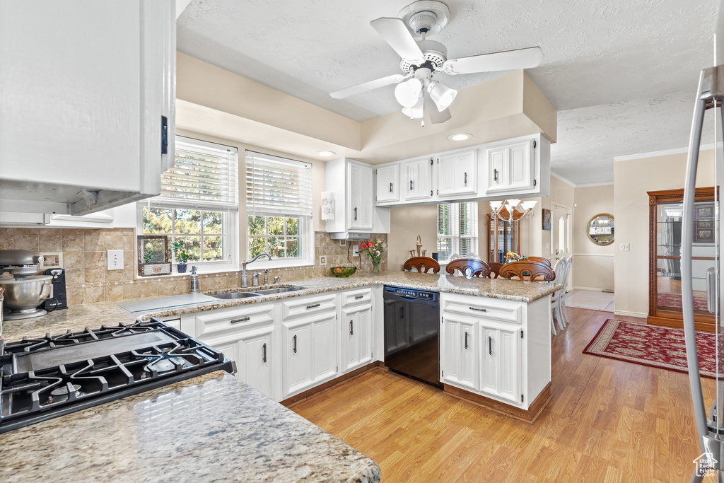 Kitchen featuring dishwasher, a peninsula, white cabinets, light wood-type flooring, and a textured ceiling