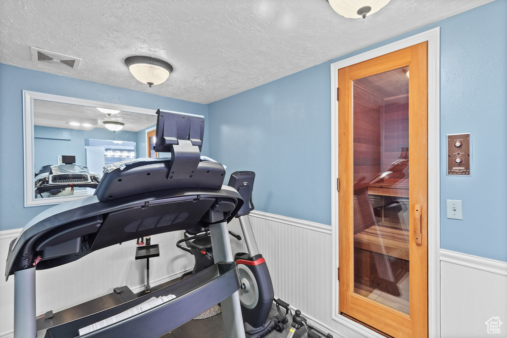 Workout area featuring a wainscoted wall and a textured ceiling
