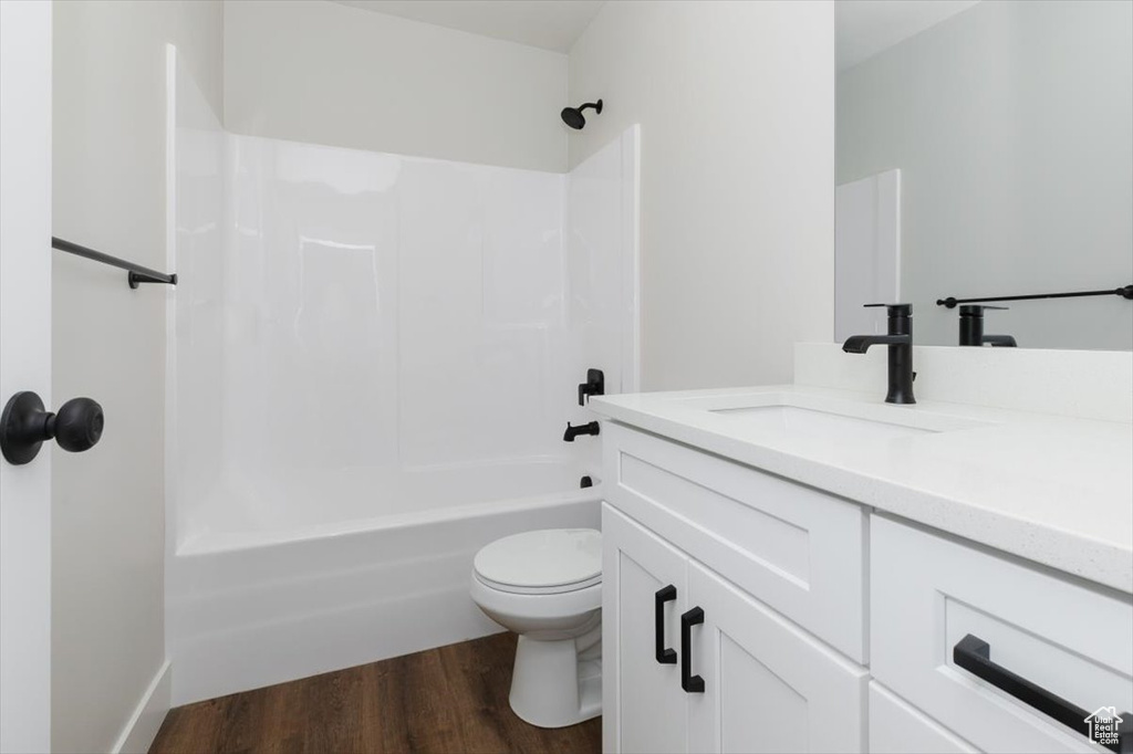 Full bath with toilet, shower / tub combination, wood finished floors, and vanity